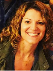 Photo of a smiling woman with curly hair and a green jacket