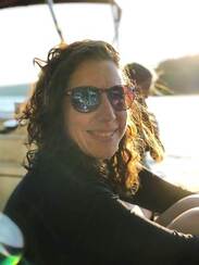 Photo of a woman wearing sunglasses and smiling with the sun on her face